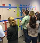 people along a large wall with rows placing sticky notes