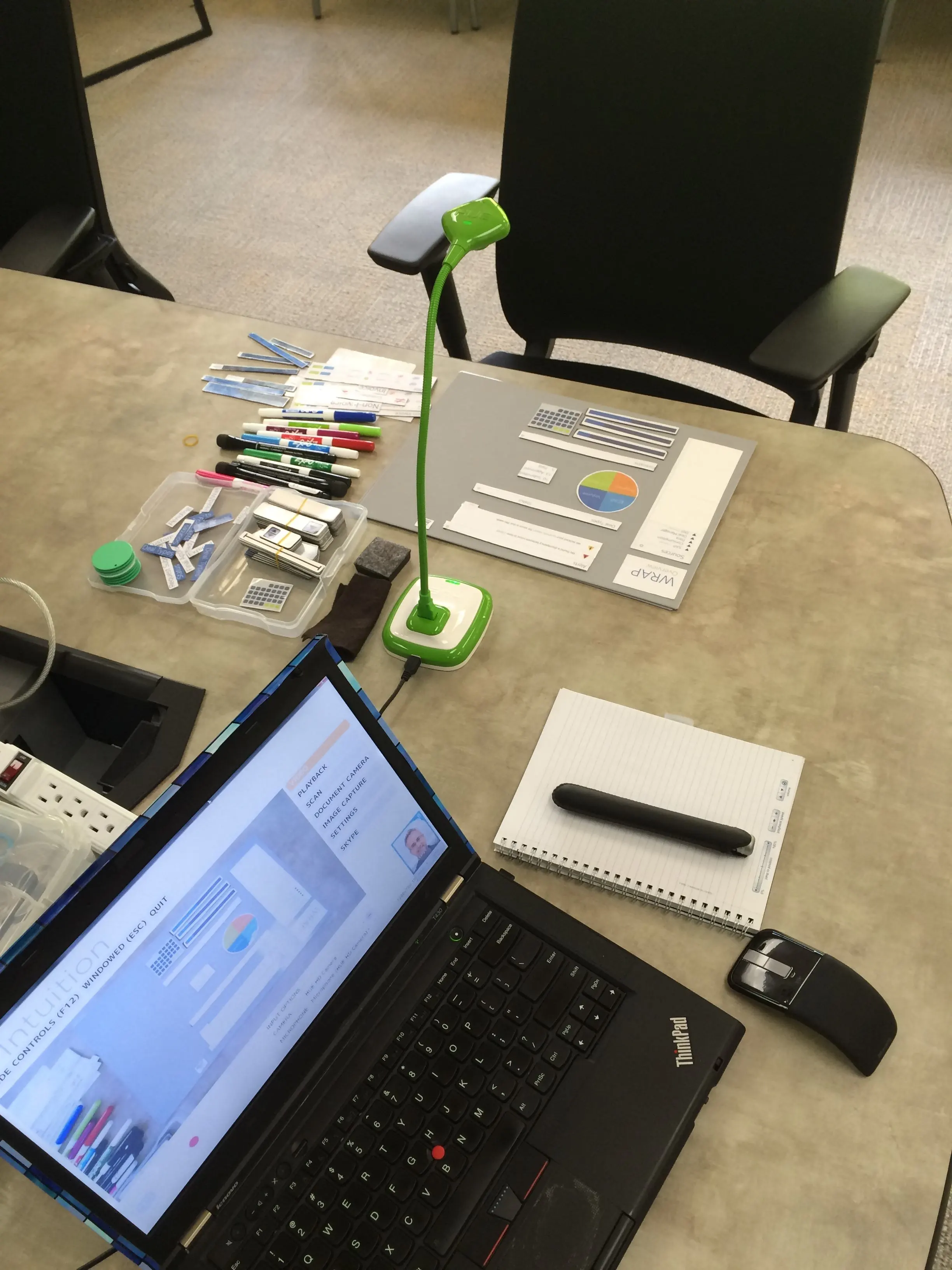 a laptop and char with a camera hovering over a board with various pieces like a puzzle